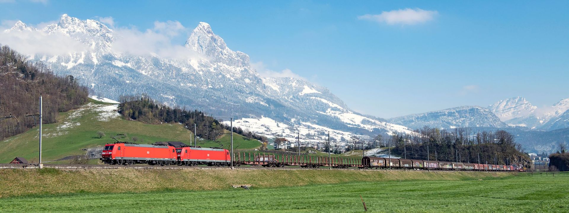 DB Cargo train running through green alpine landscape