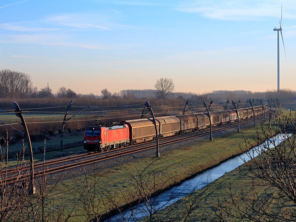 Cargo train running through a green landscape at dusk