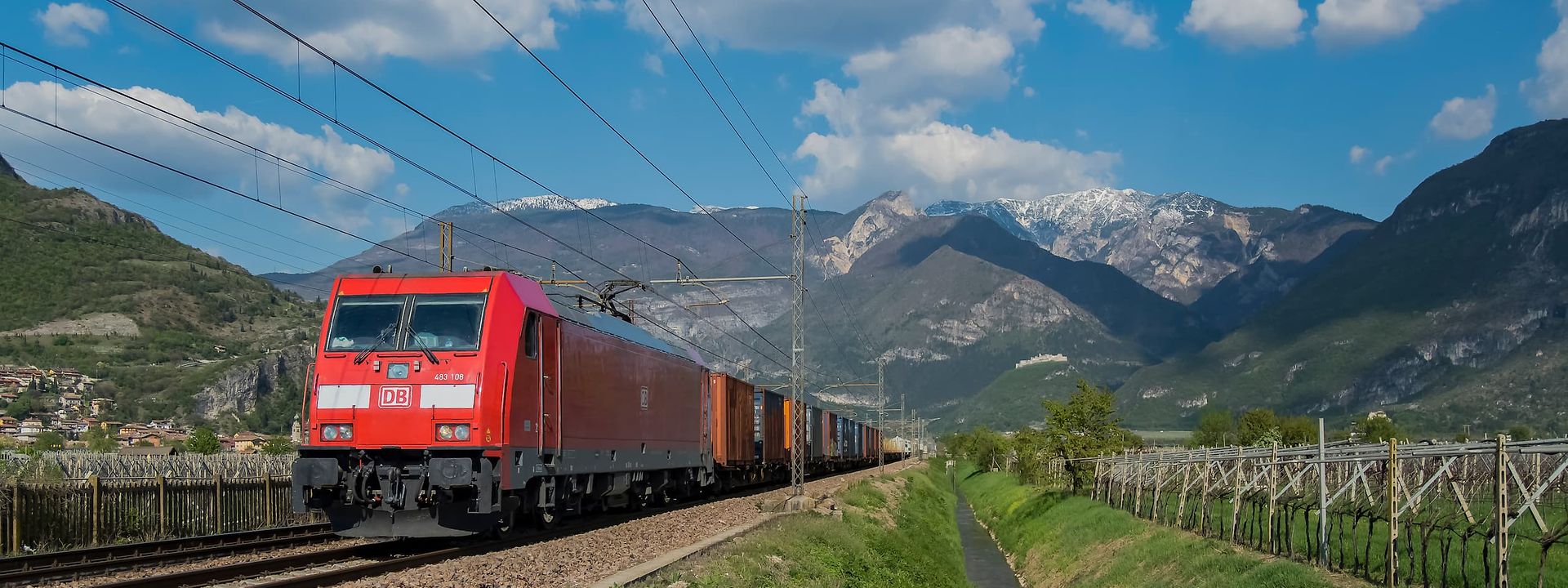 DB Cargo train running through a green alpine landscape